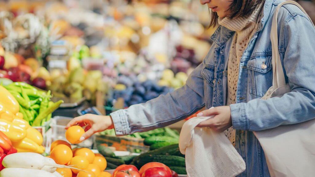 Woman picking oranges at a supermarket.