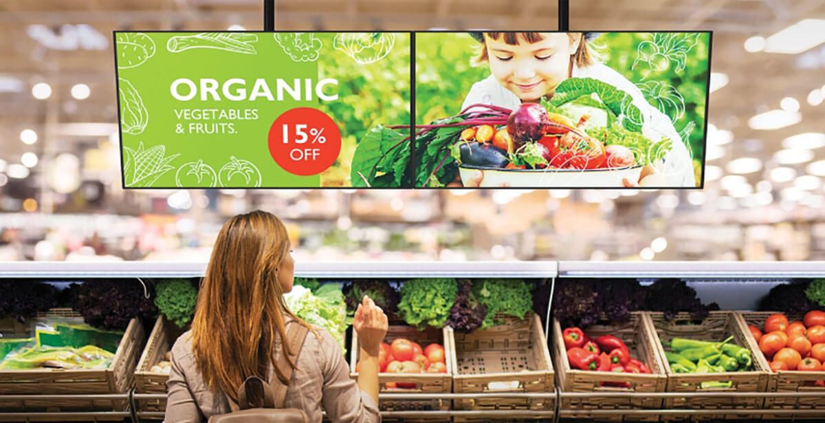 A woman standing in front of the fresh produce aisle.