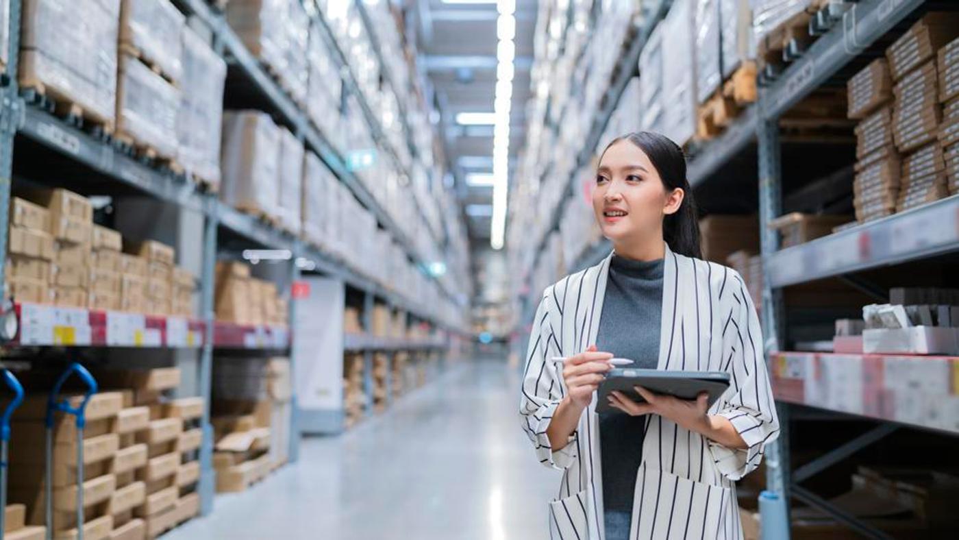 A woman in a warehouse tracking the inventory using a tablet. 