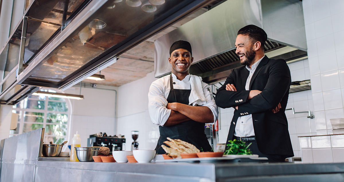 Two chefs happily smiling in a kitchen.
