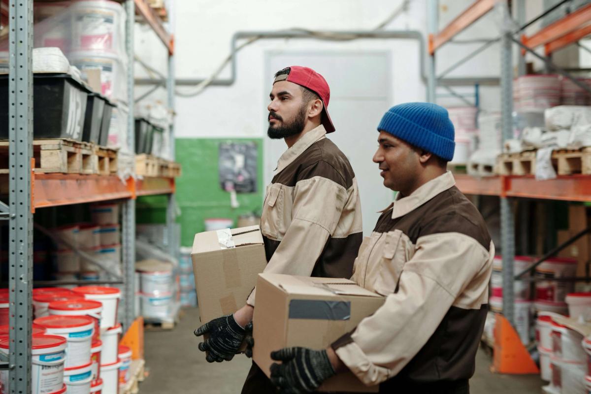 Two men lifting boxes in a warehouse.