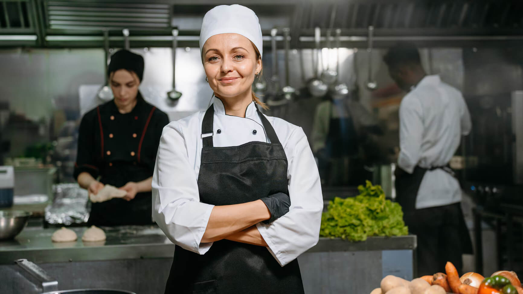 A woman chef standing proudly in a kitchen.