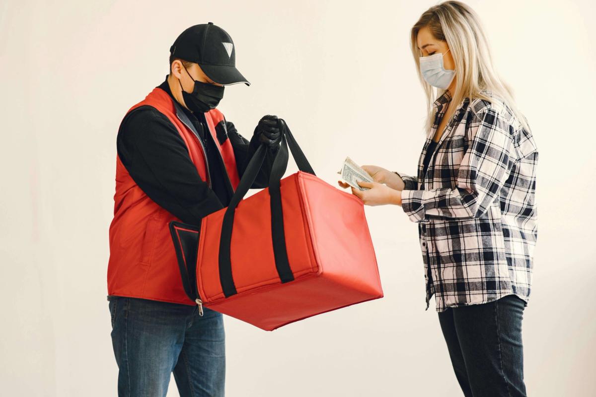 A delivery man handing the food to a woman. 