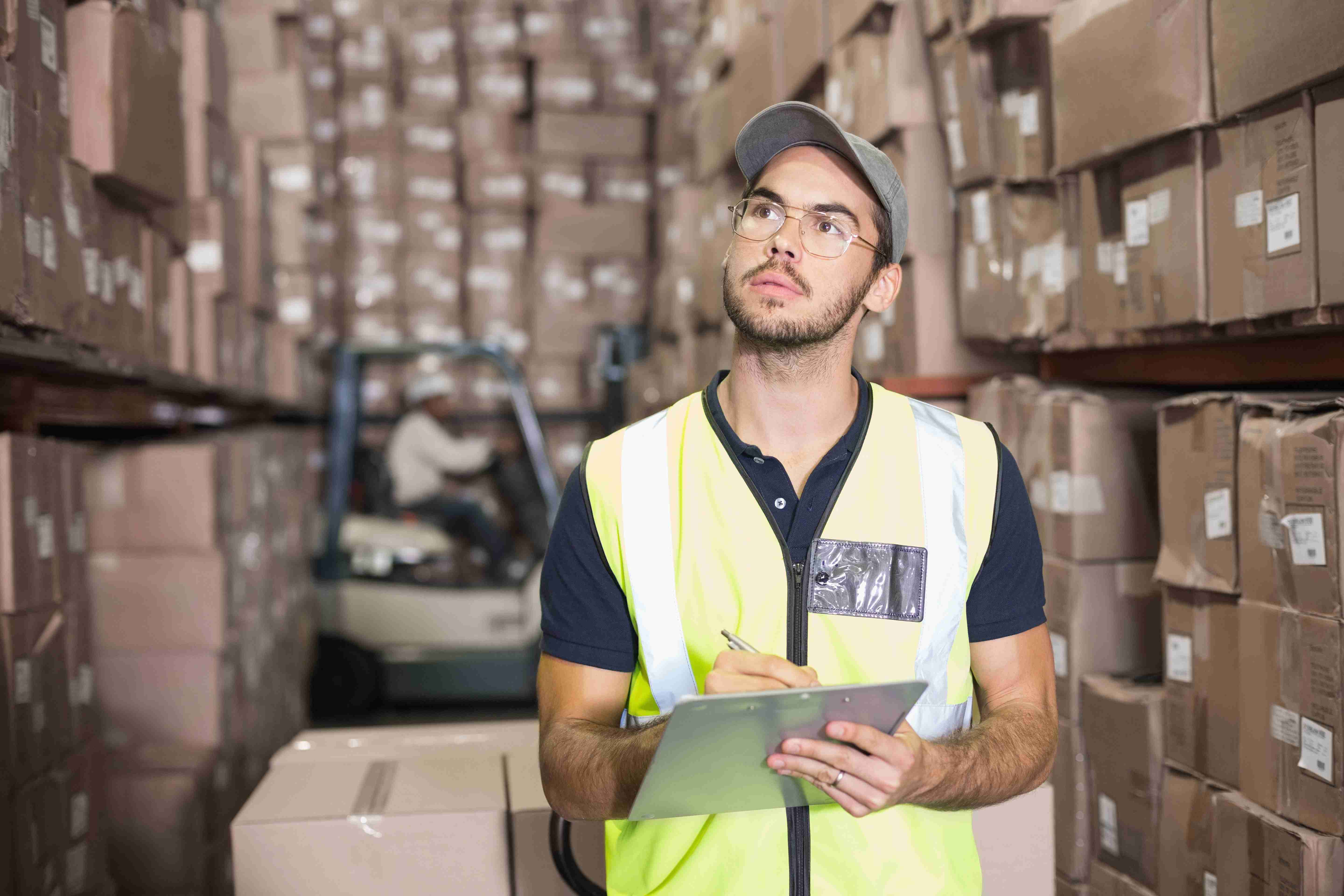 Warehouse worker using a clipboard among boxes.