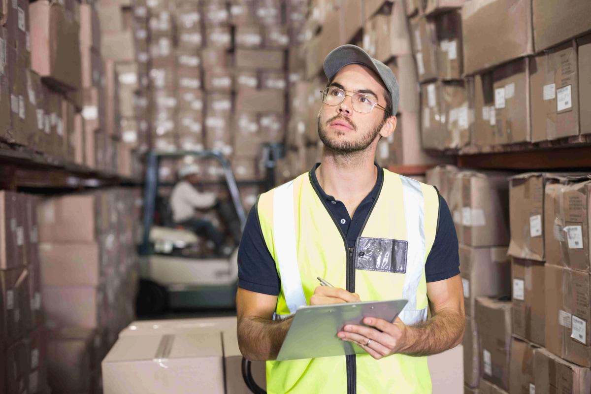 Warehouse worker using a clipboard among boxes.