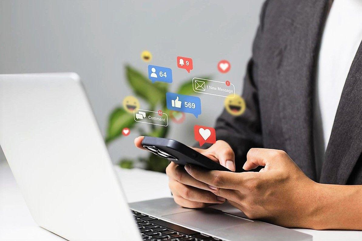 A man in a suit engaged with his phone and laptop.