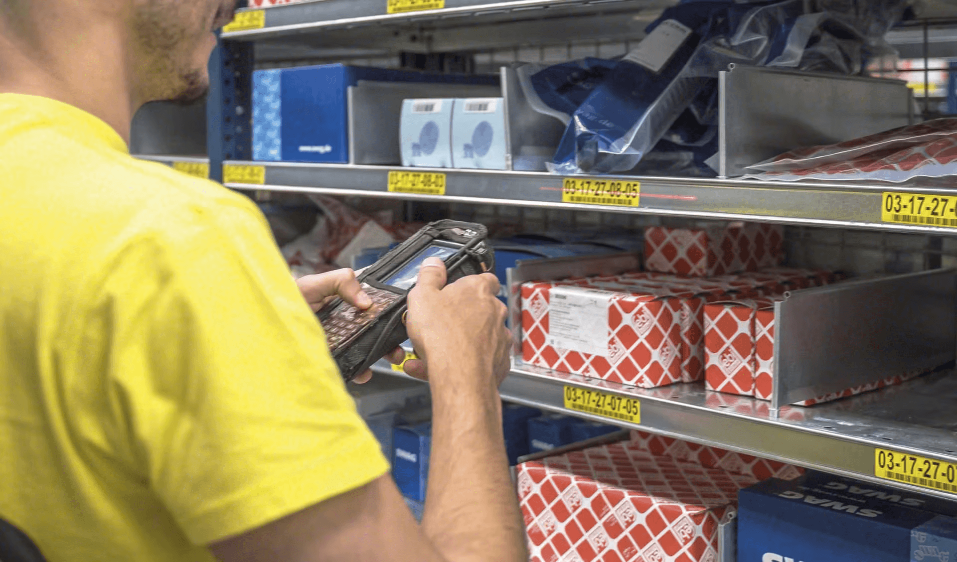 Worker using a handheld scanner to pick items from warehouse shelves.