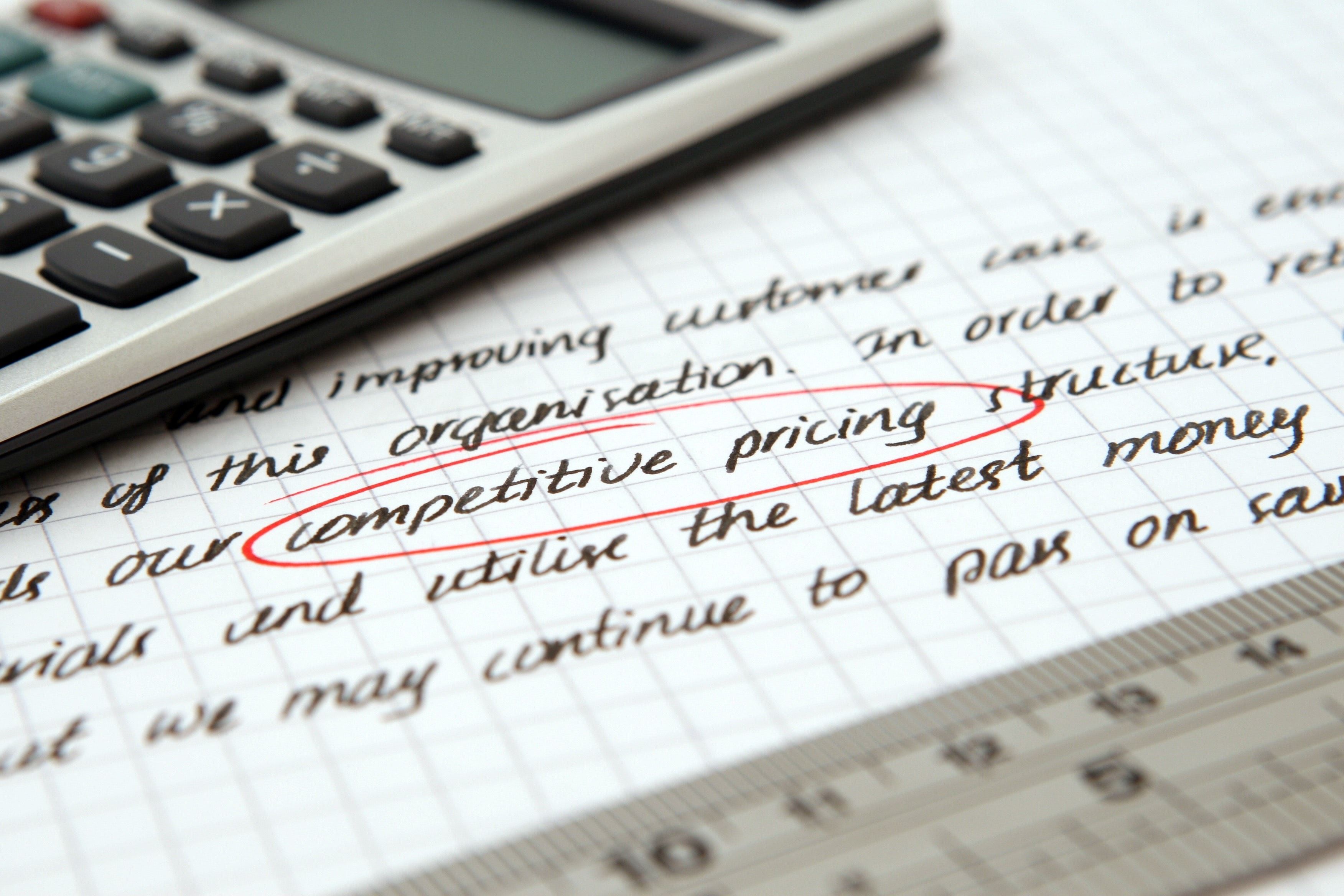 A paper with text with the word competitive pricing encircled and a calculator on top of the paper. 
