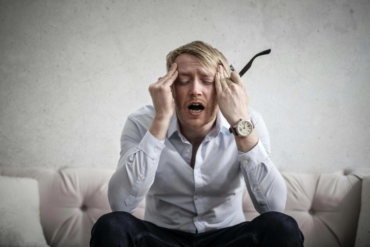 A confused man touching his head.