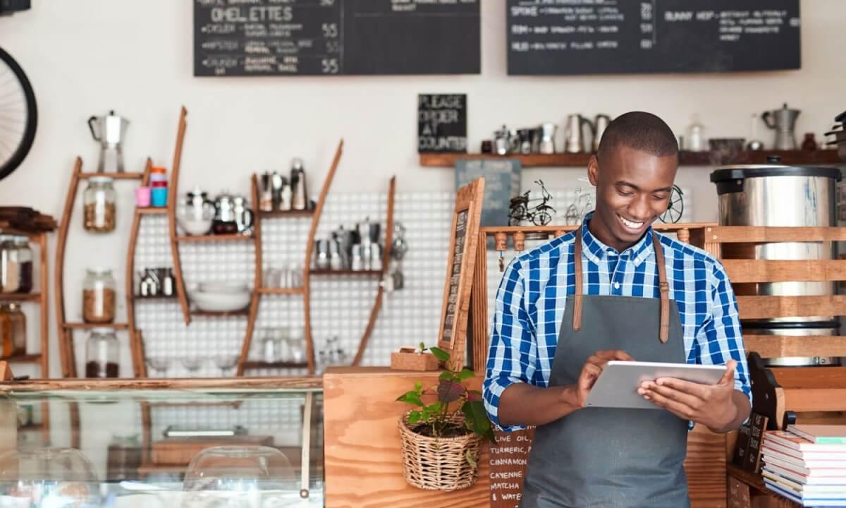 Server in a café holding a tablet, managing orders digitally.