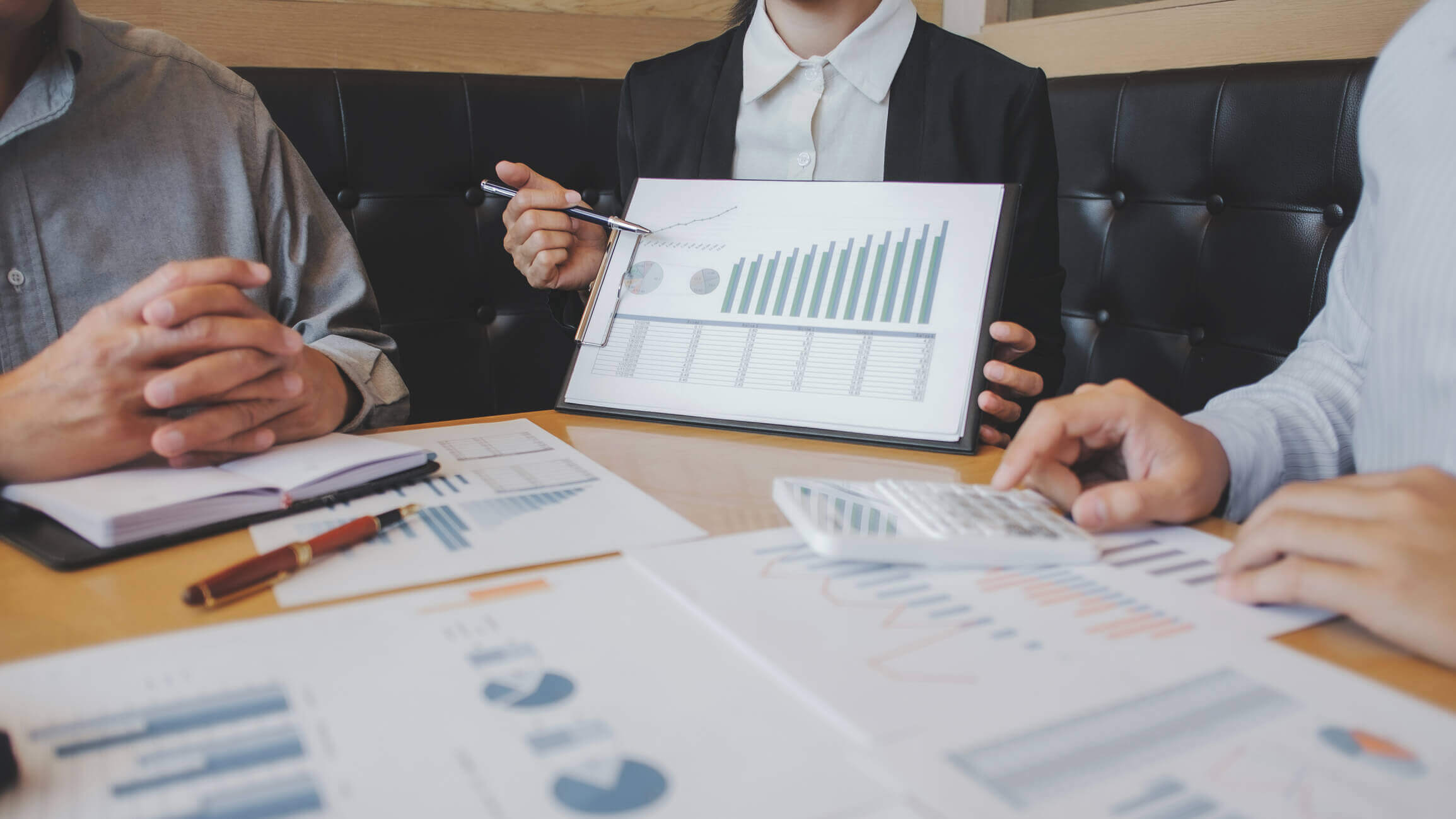A group of people discussing and analysing data reports in an office setting to make business decisions.