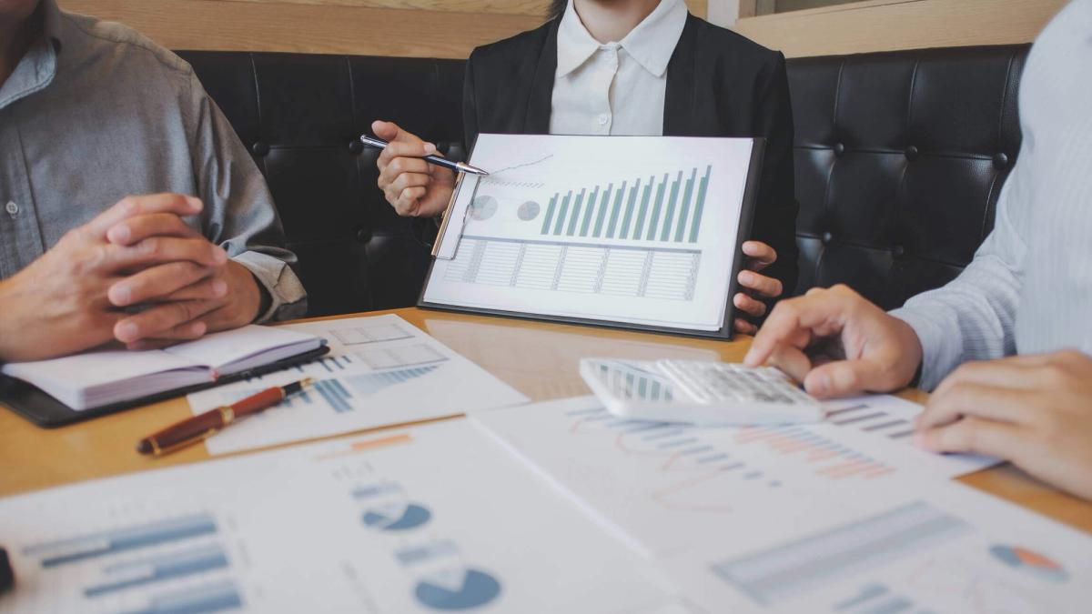 A group of people discussing and analysing data reports in an office setting to make business decisions.
