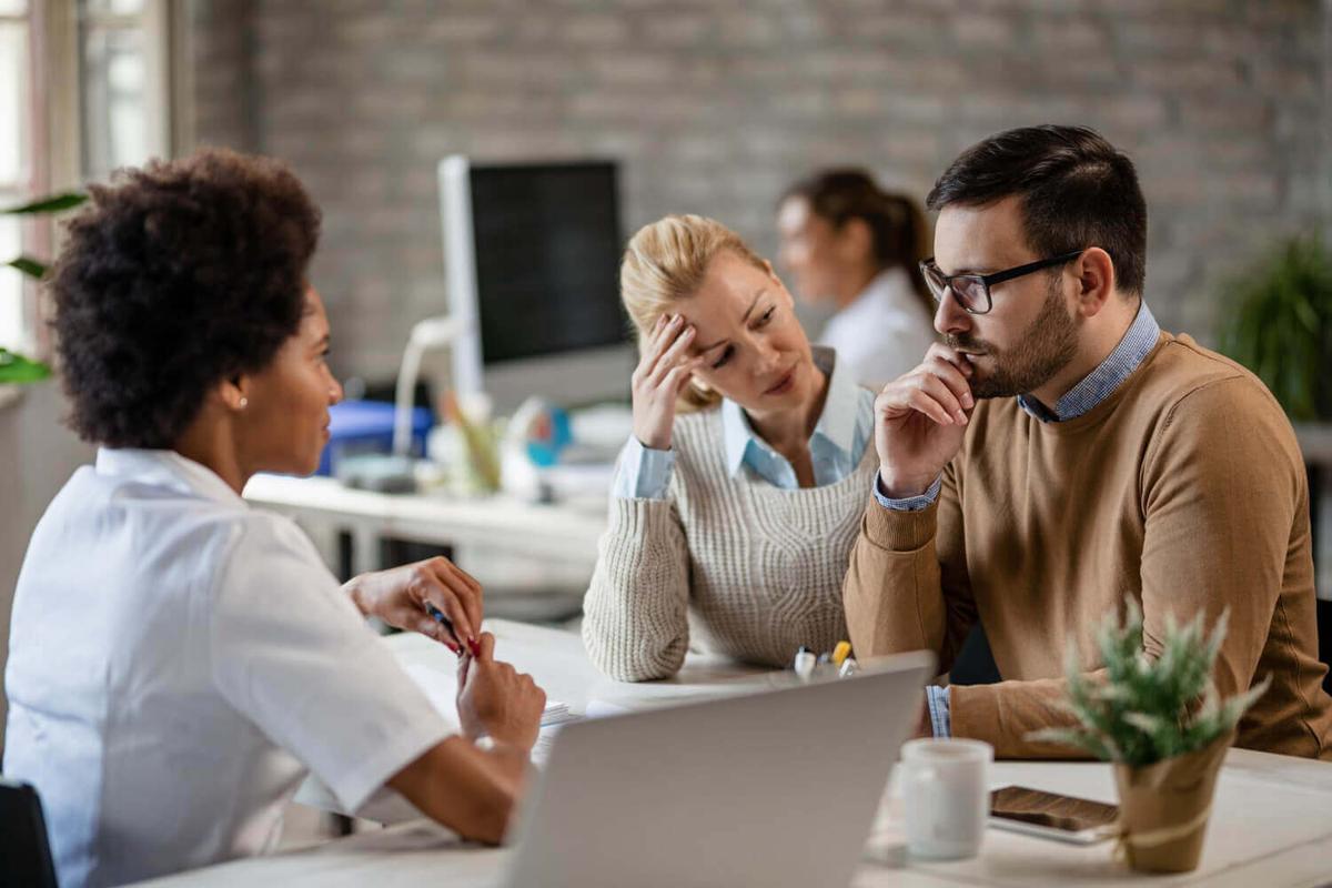 Three people at a table, looking confused and frustrated.