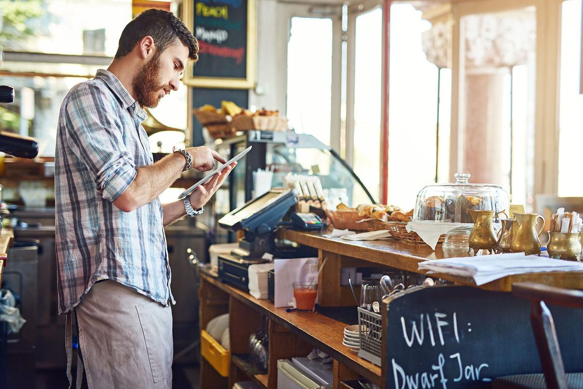A person using a tablet while standing in front of a counter.