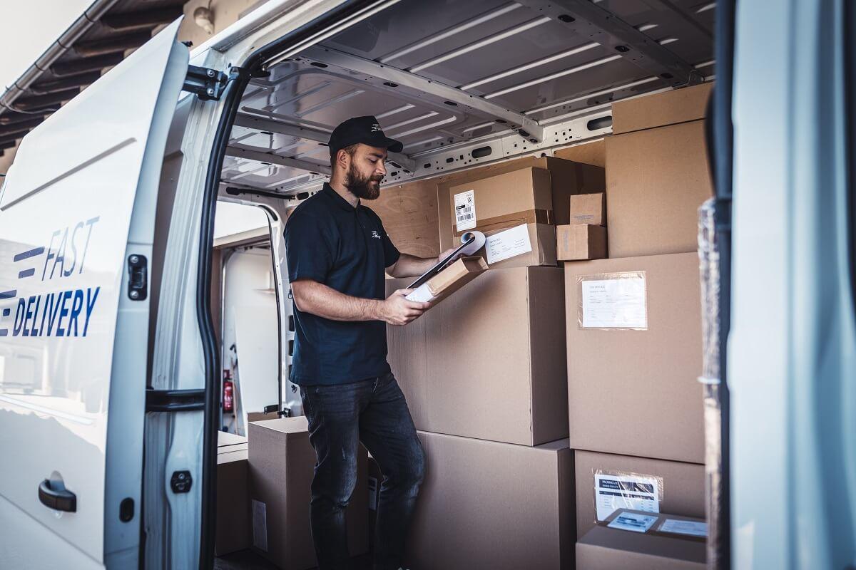 A man checking the goods inside a delivery van.