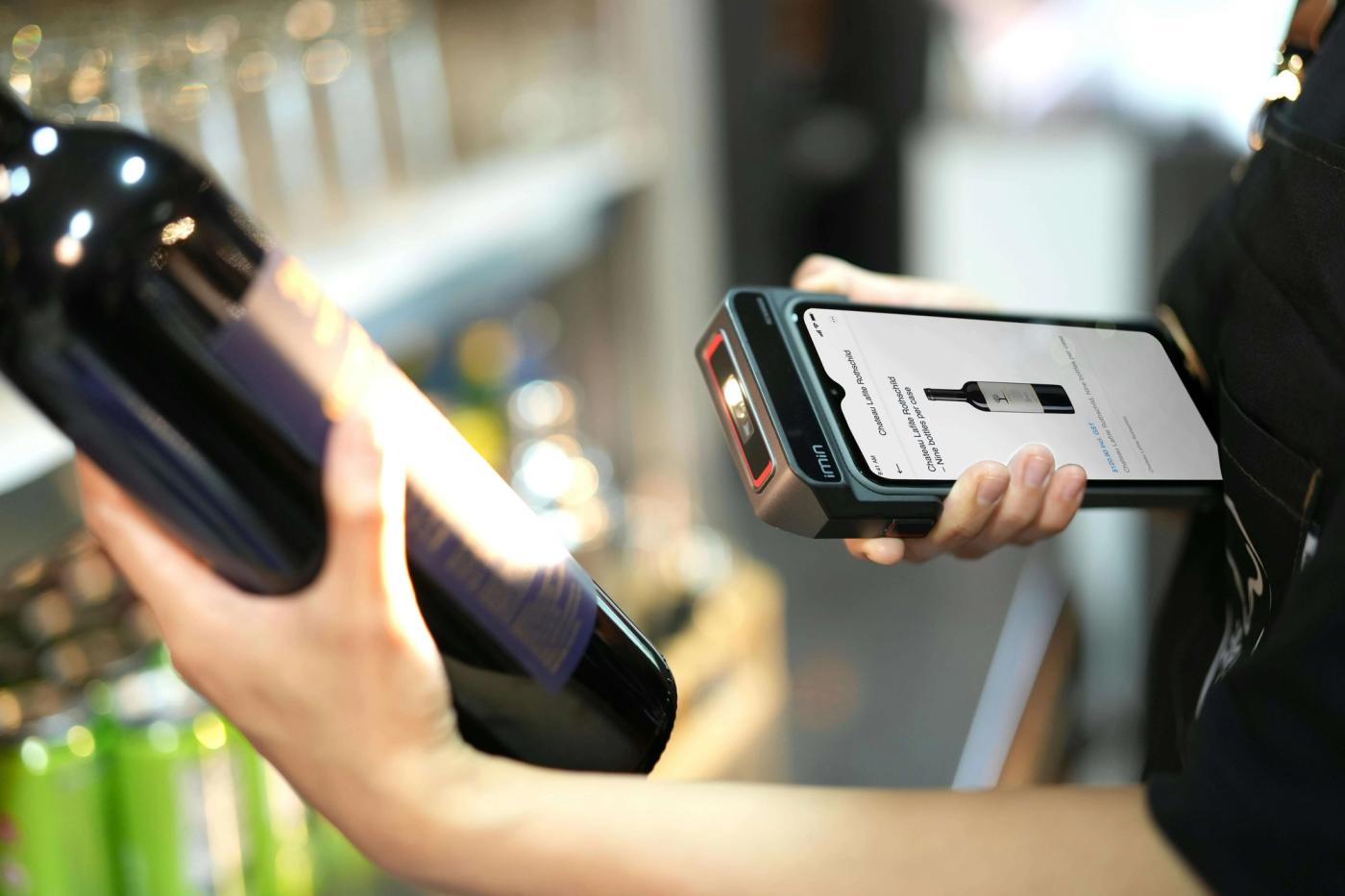 A person using a scanner on a bottle of wine.