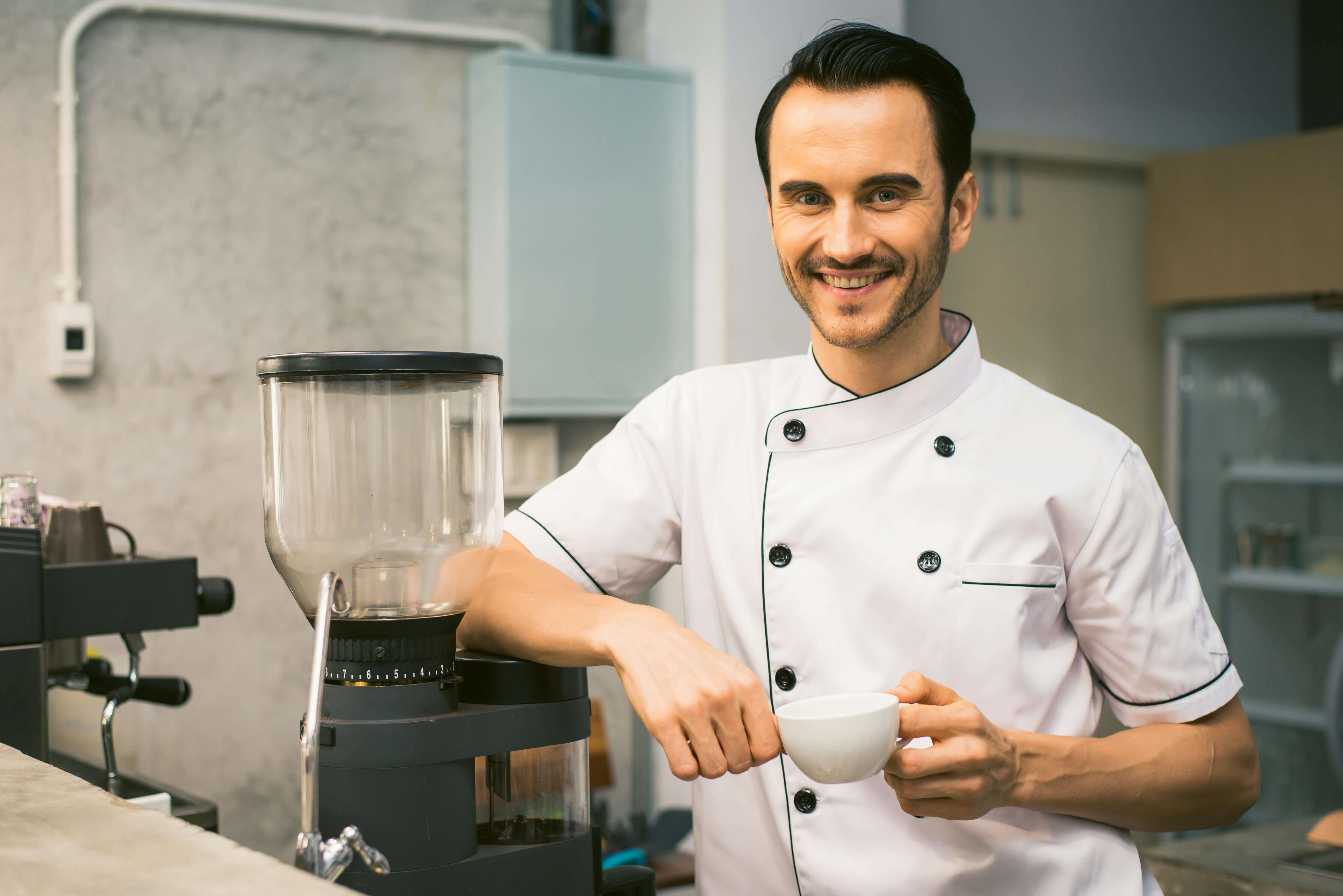 Smiling chef holding white tea cup.