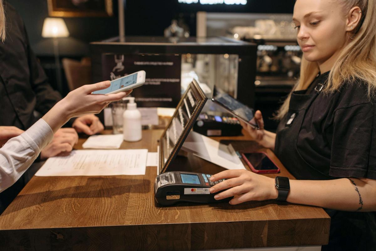A young woman using a POS system at a retail counter.
