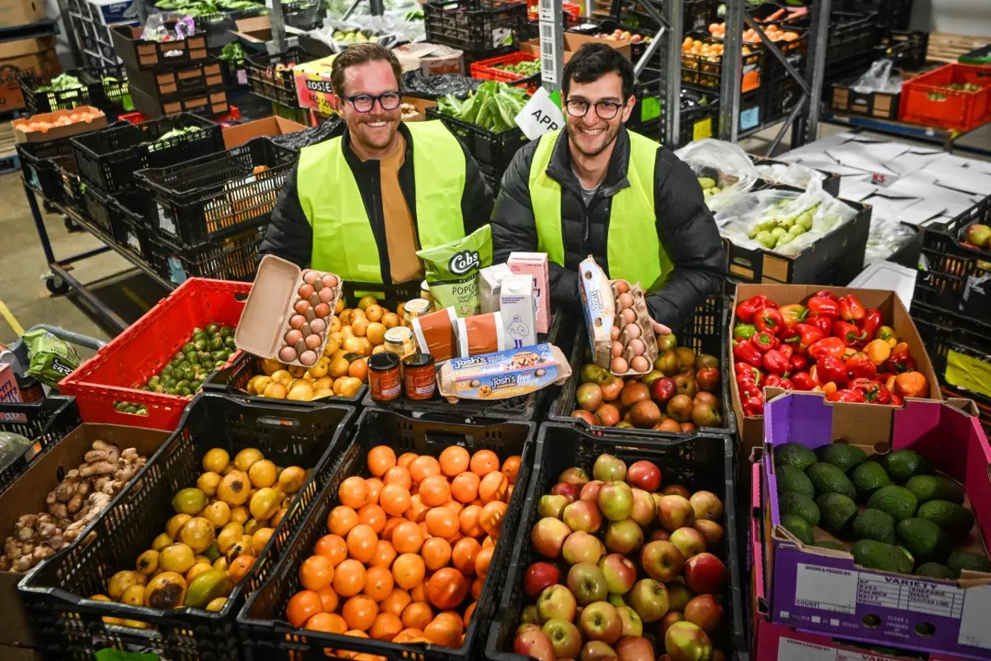 Two men in a warehouse full of fruits and vegetables.
