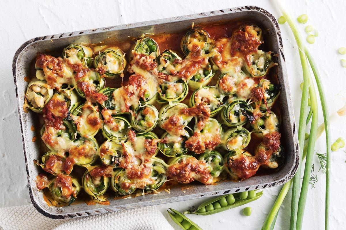 A casserole dish filled with vibrant green peas topped with melted cheese.