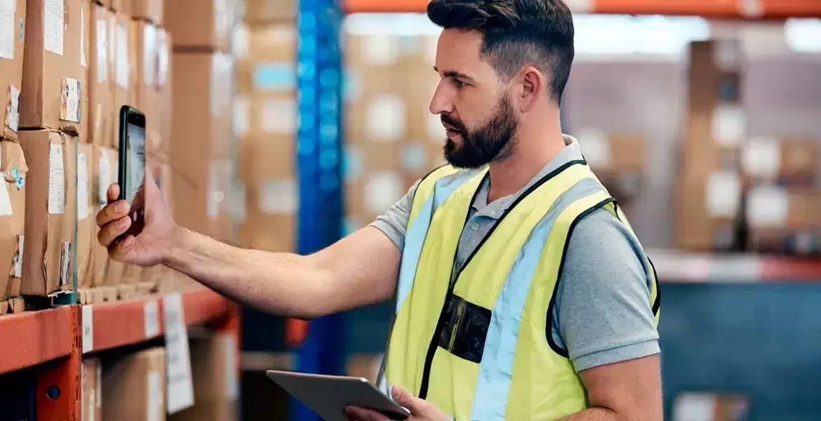 A man scanning a product barcode in a warehouse to track inventory.