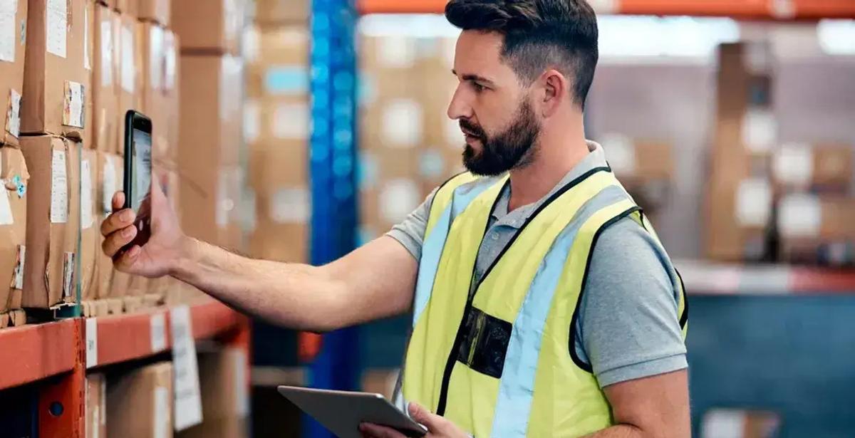 A man scanning a product barcode in a warehouse to track inventory.