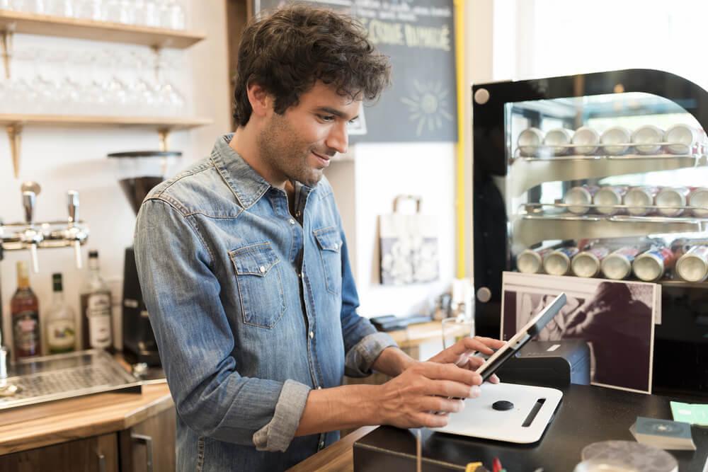 A man in a cafe holding a tablet.