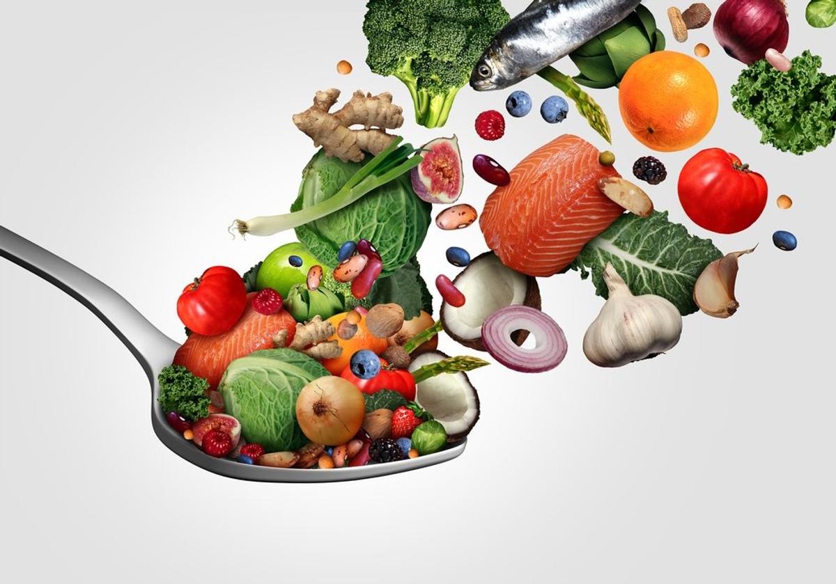 A spoon brimming with a variety of fish, fresh fruits, and vegetables, highlighting a colorful and nutritious selection.
