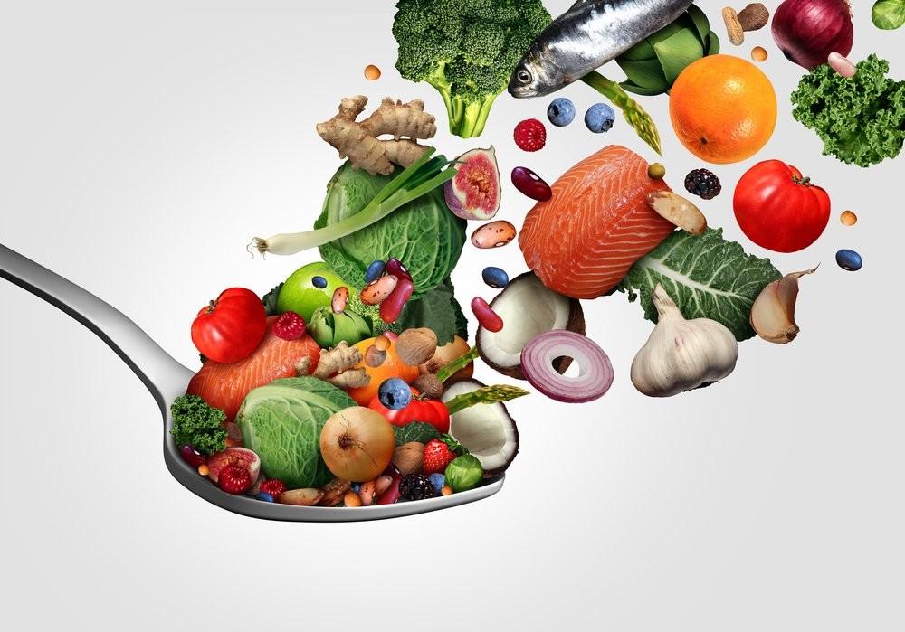 A spoon brimming with a variety of fish, fresh fruits, and vegetables, highlighting a colorful and nutritious selection.