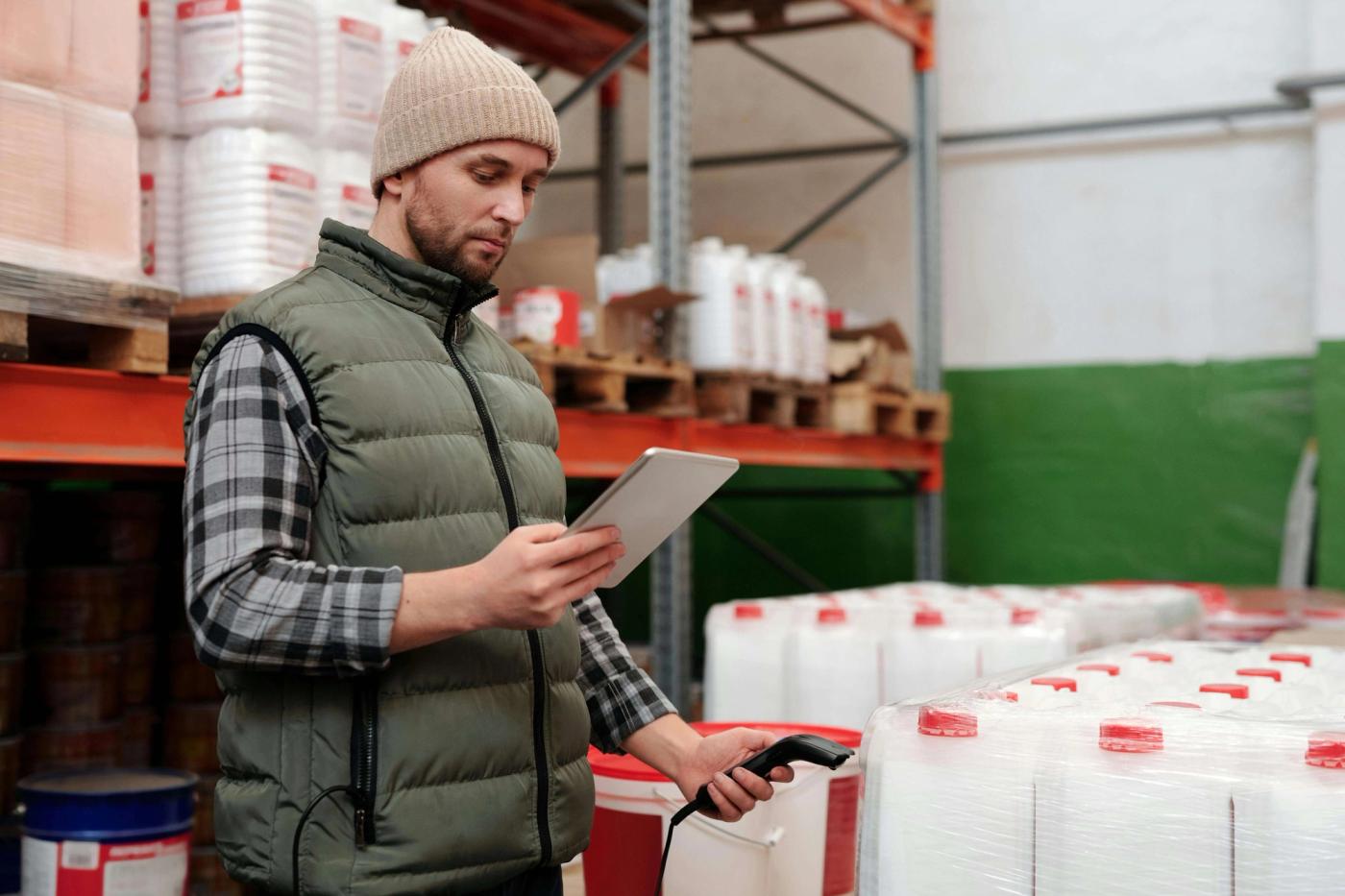 A man using a tablet and a bar code scanner to take inventory.