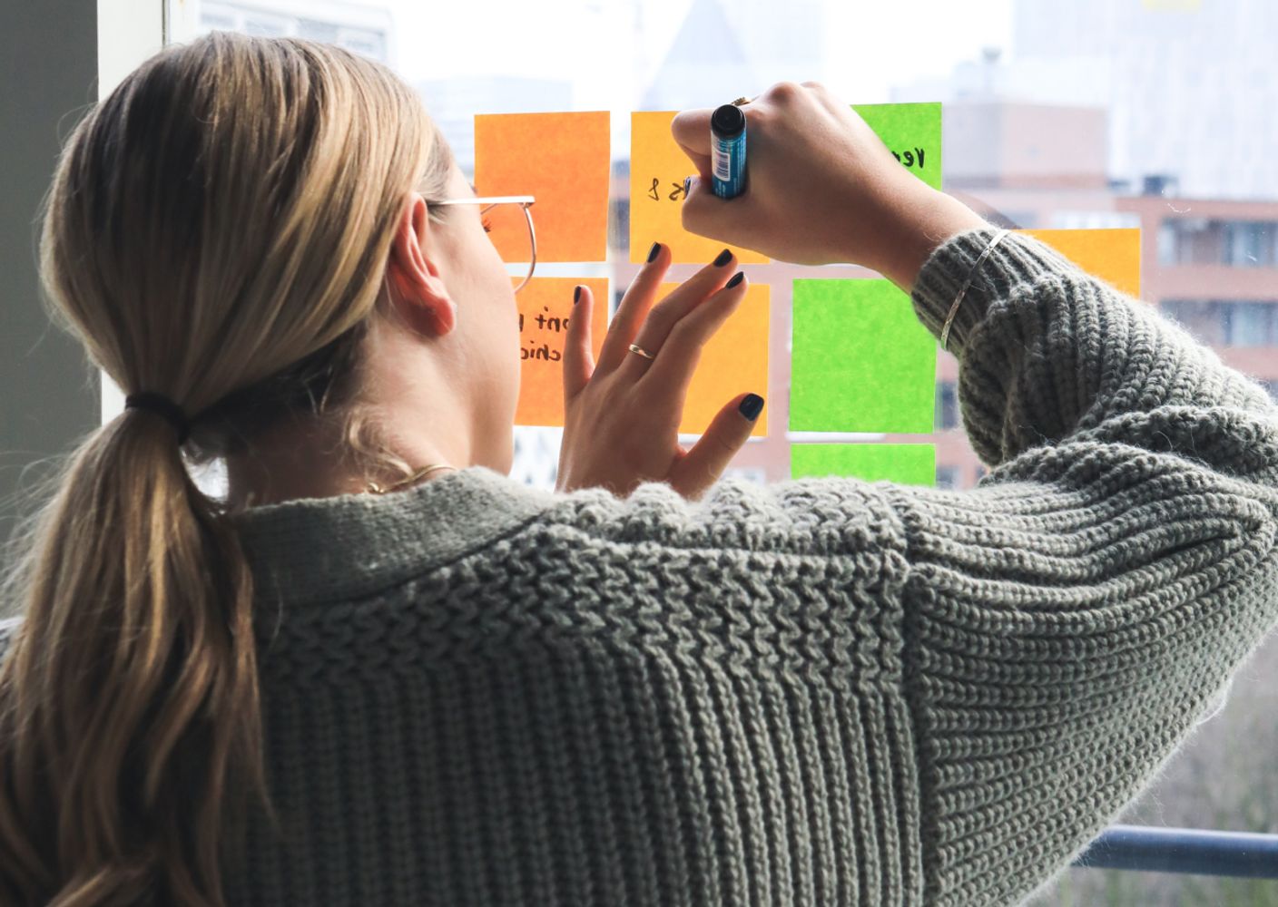 A woman writes on post it notes against a window