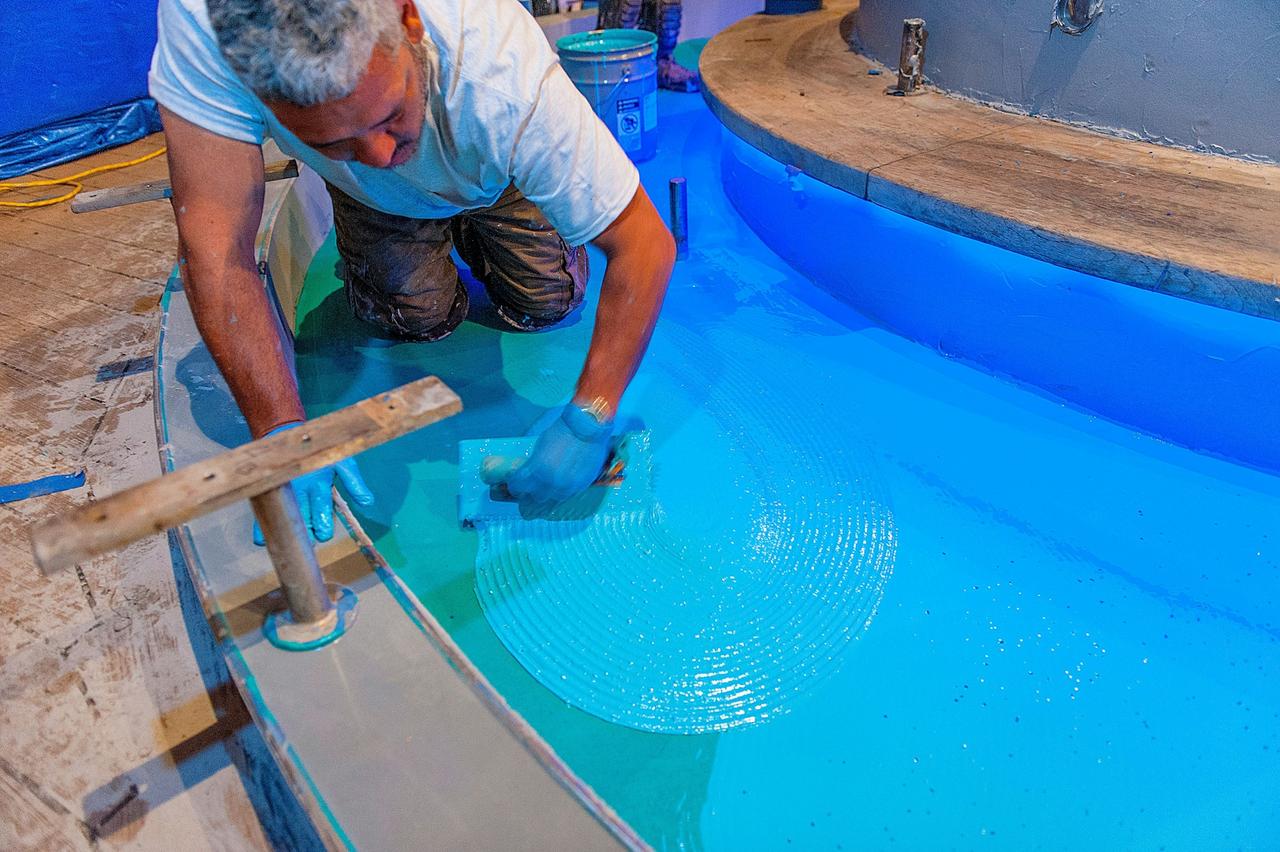 Worker smoothing out decking on the Carnival Inspiration