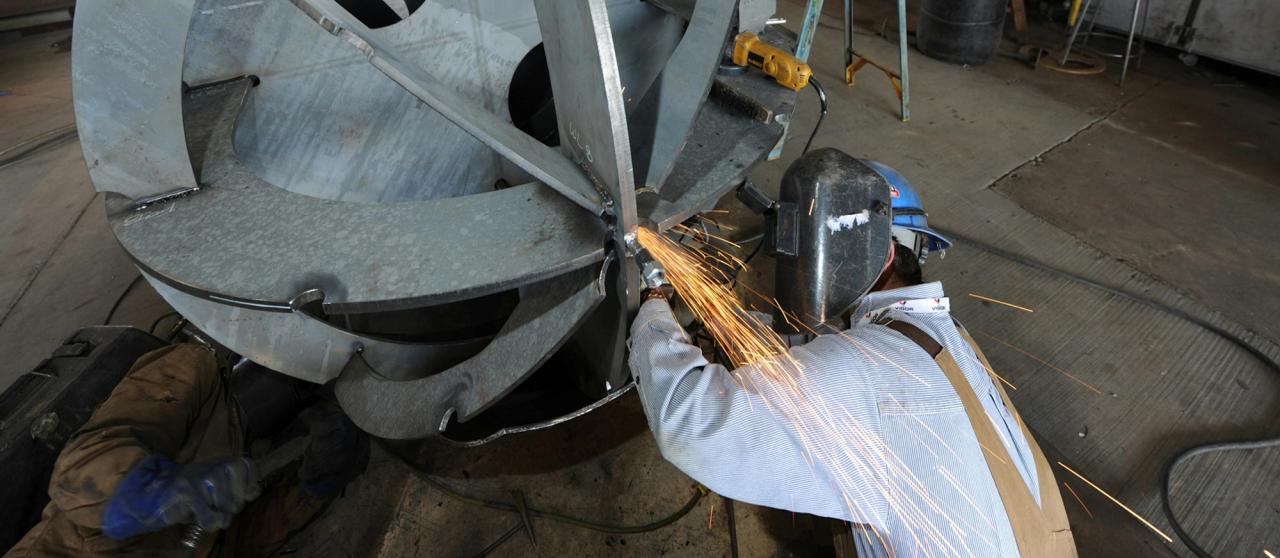 Worker welding a large piece of machinery