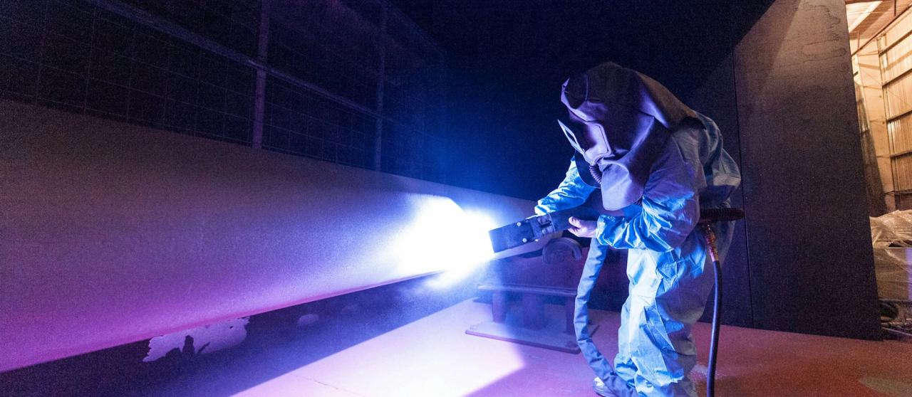 Worker in a heat suit welding heavy machinery