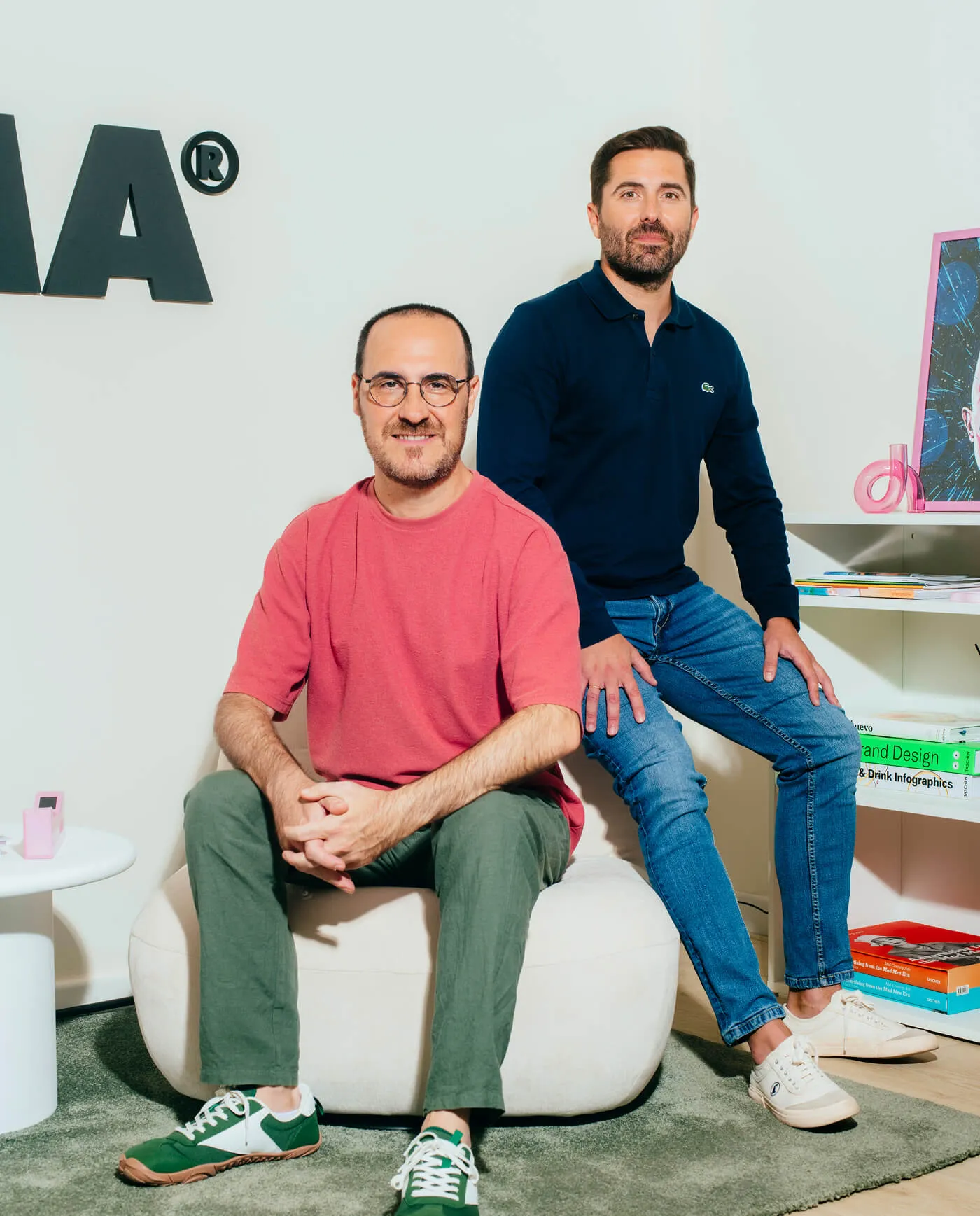 Ángel y Nacho, fundadores de GOMA, retratados de pie sobre fondo gris.