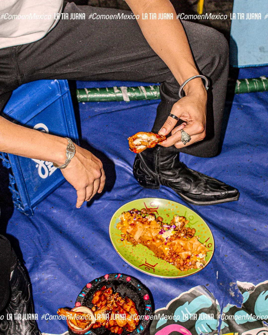 Comensal con botas vaqueras sentado en el suelo junto a un plato de comida