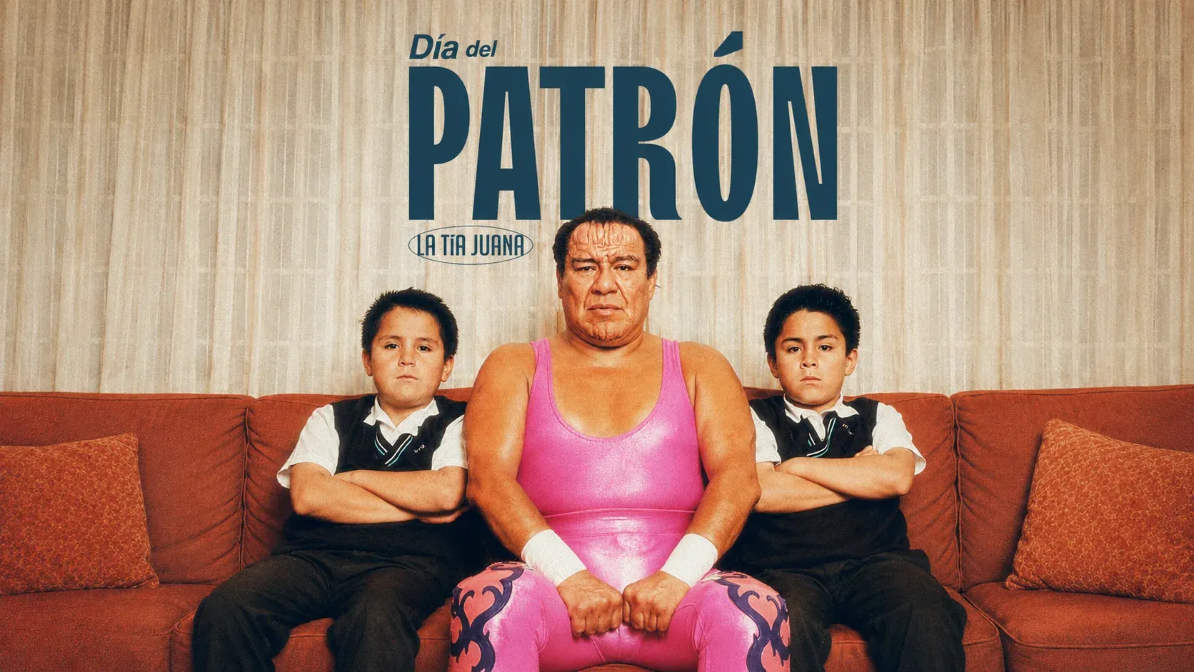 Pieza “Día del Patrón”: una luchadora con máscara rosa posa en un sofá entre dos niños vestidos de escolares