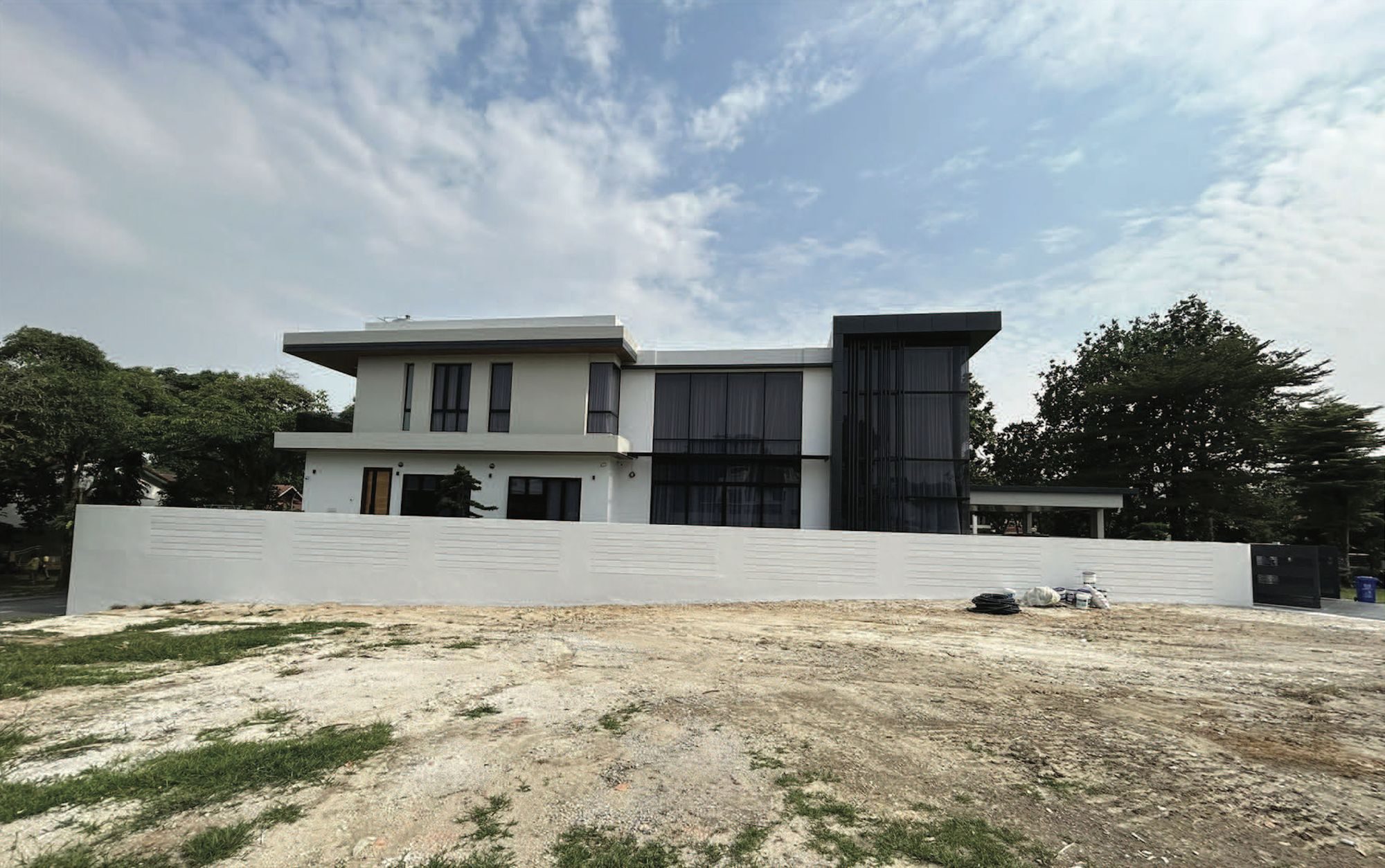 Side elevation: a white two-storey volume with deep eaves beside a dark double-height glazed bay, behind a long white boundary wall
