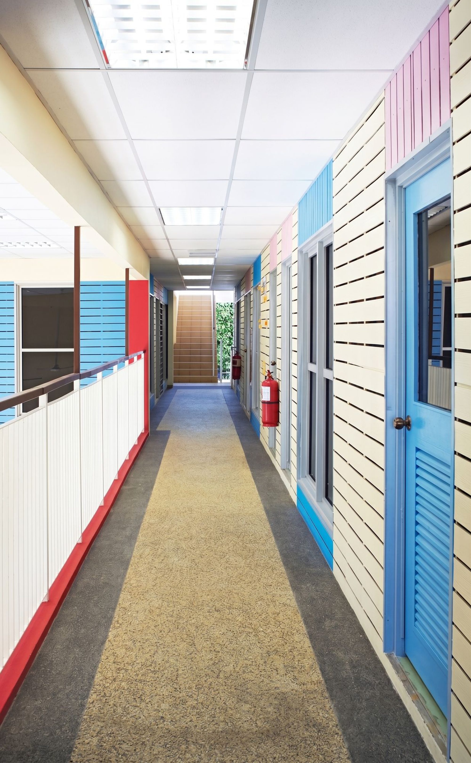 Upper-floor corridor lined with painted cement-plank container walls