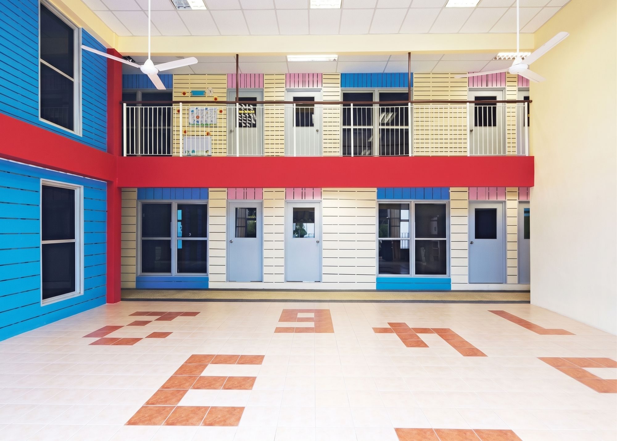 Double-volume assembly hall with large numerals set into the floor tiles, overlooked by a bridge