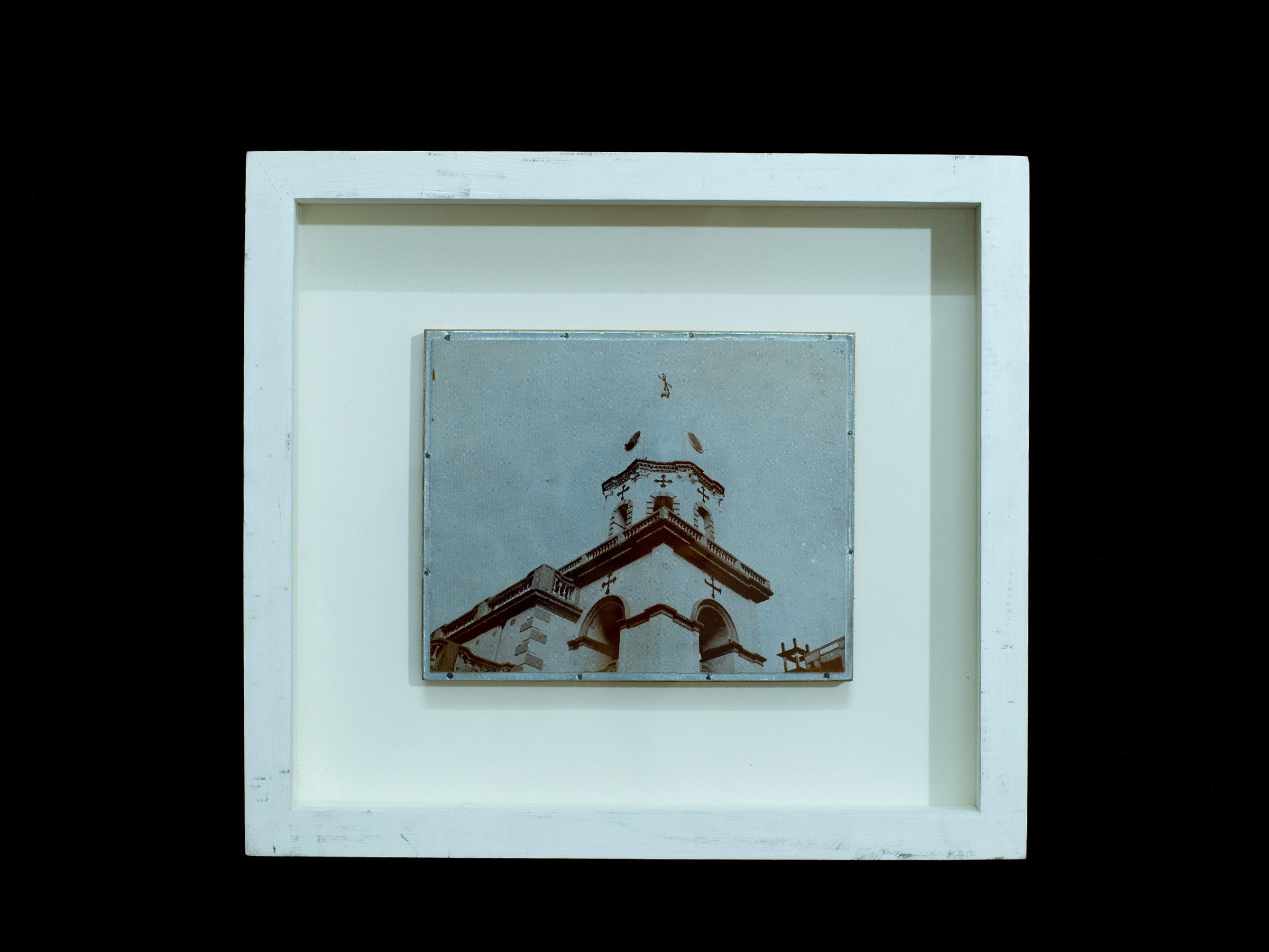Small zinc plate depicting a church facade and cross displayed in a white frame.