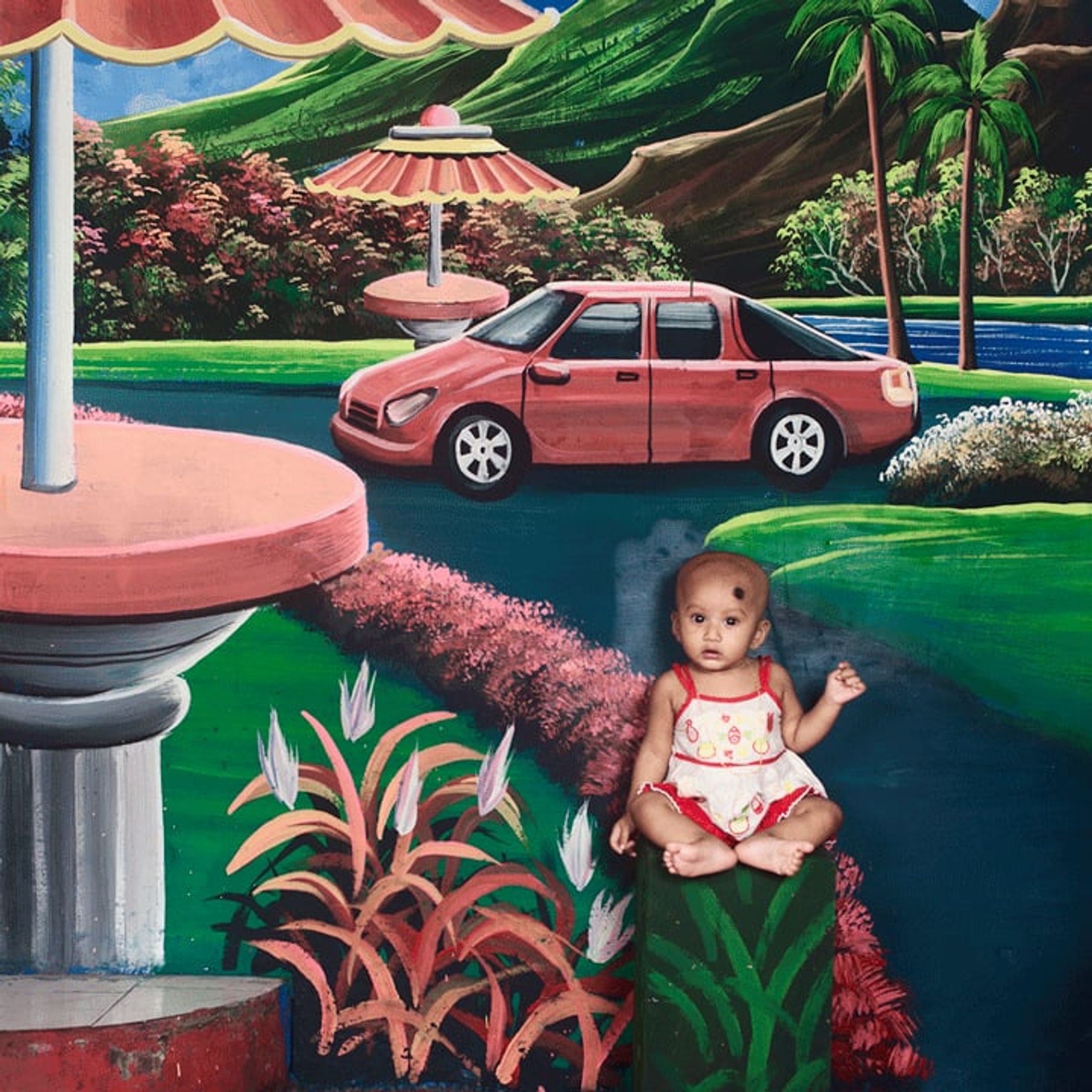 Young person in red clothing and a cowboy hat poses before a painted riverside scene.