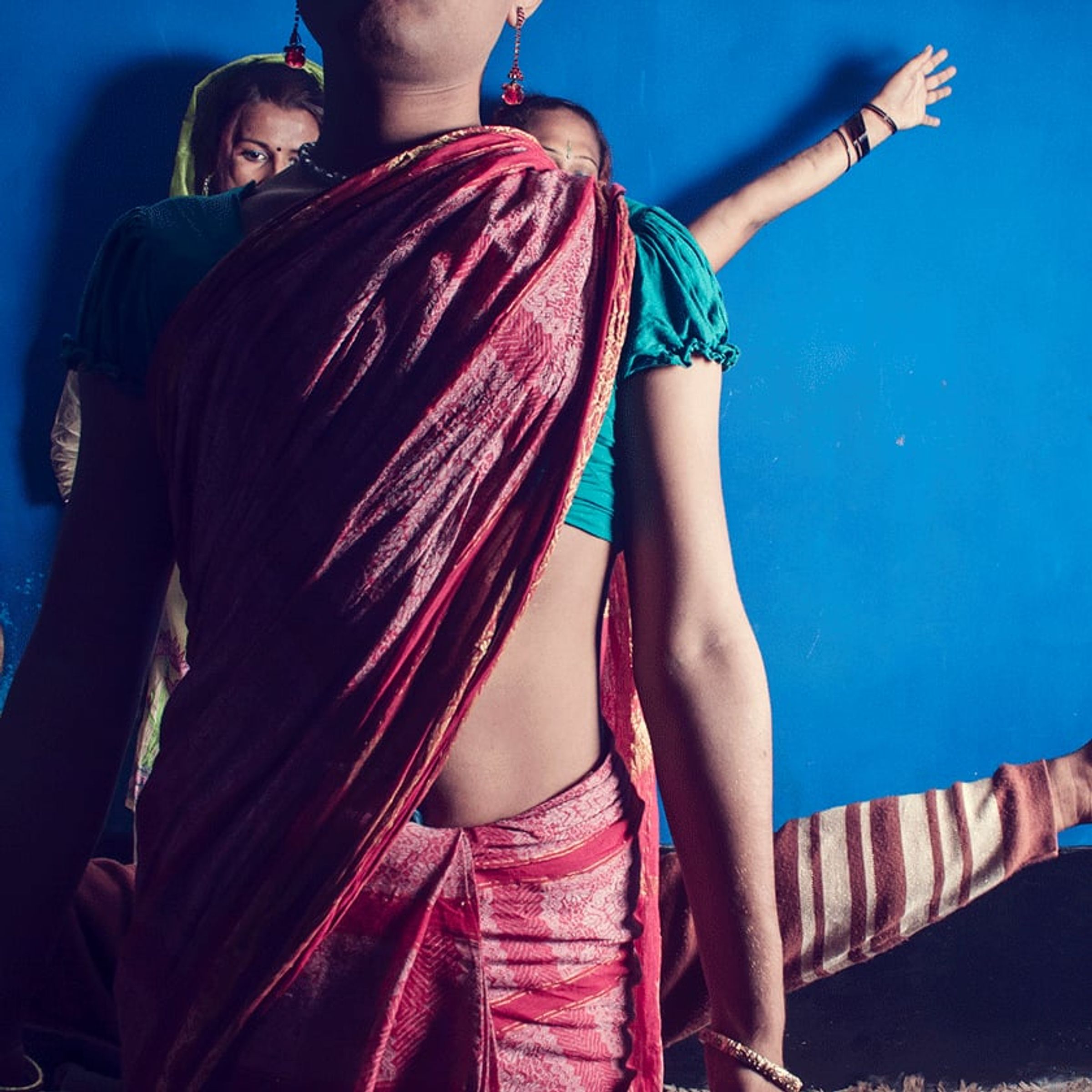 Person in a deep purple sari faces away with one arm extended.