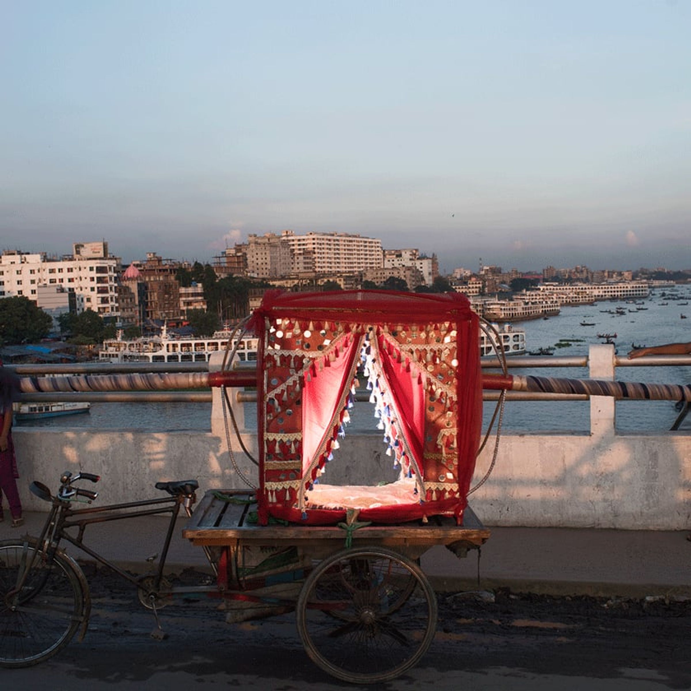 Decorated three-wheeled cart stands on a rooftop overlooking dense city buildings.