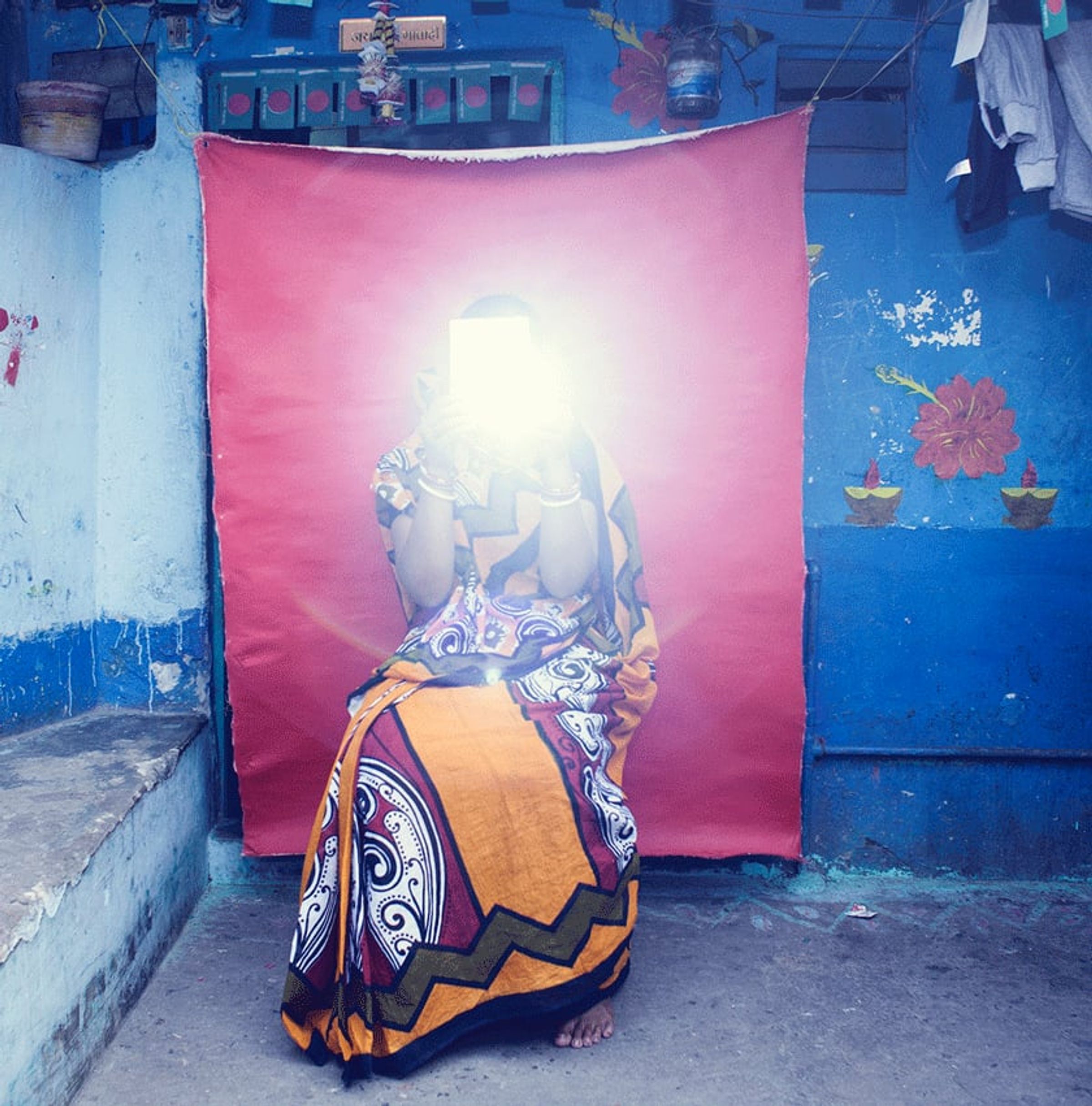 Seated person in patterned clothing is obscured by a bright camera flash.