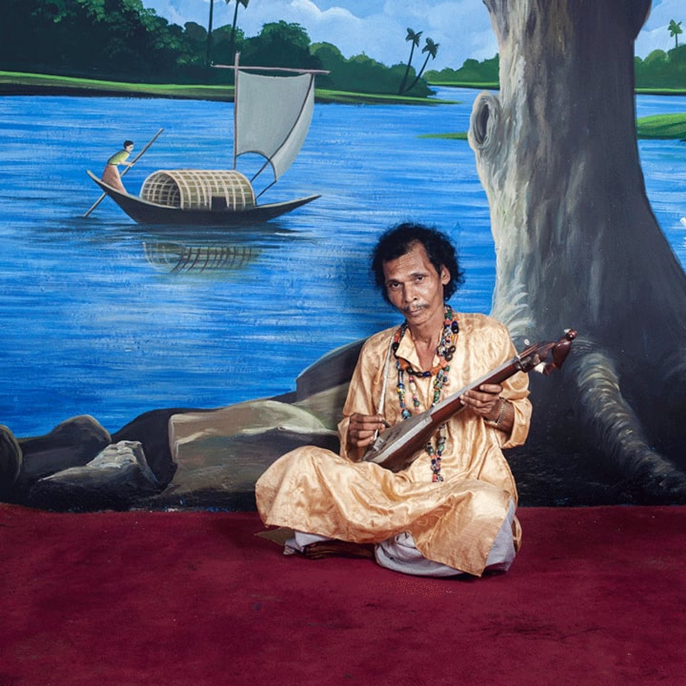 Seated musician holds a string instrument before a painted riverside tree and boat.