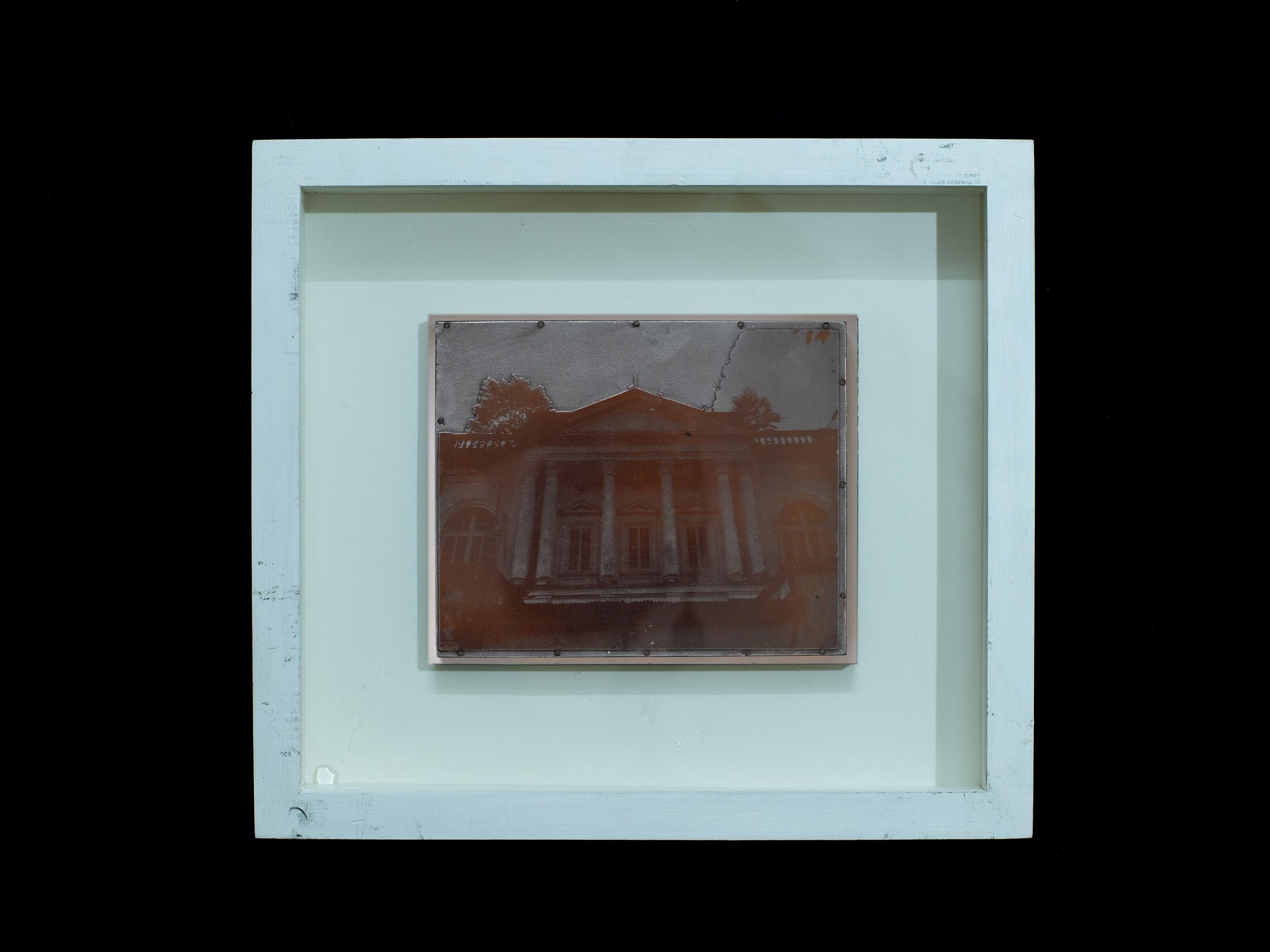 Reddish zinc plate depicting the front of a historic building displayed in a white frame.