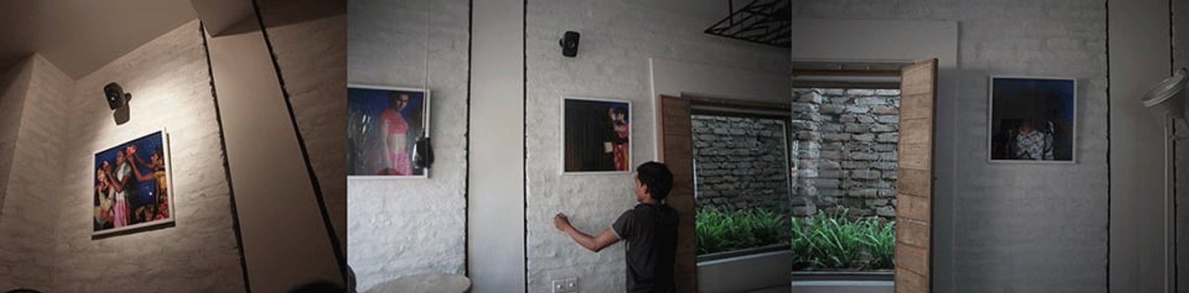Panoramic gallery installation with framed portraits displayed across white and gray walls.