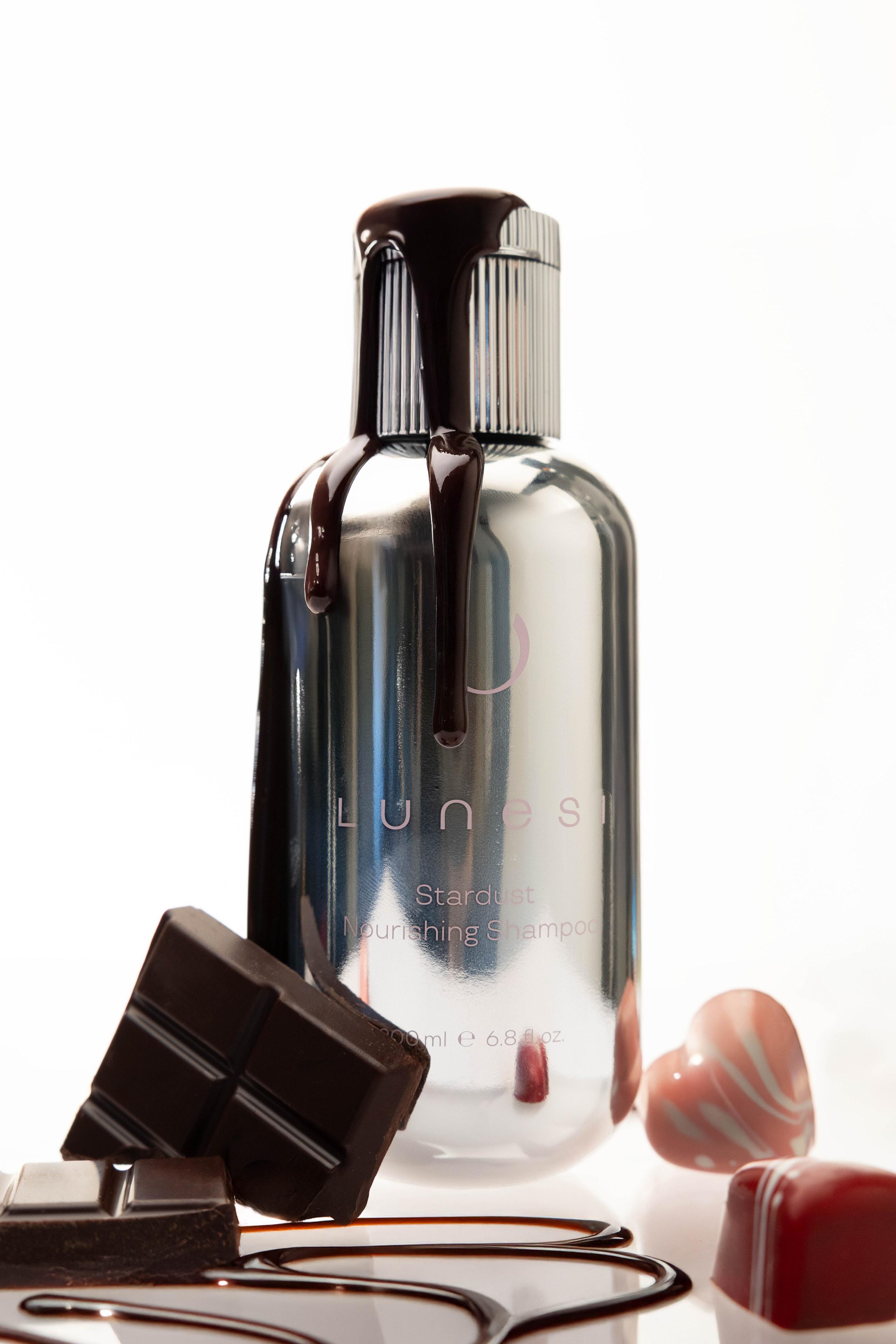Chrome Lunesi Stardust Nourishing Shampoo bottle dripping chocolate beside chocolate squares and hearts