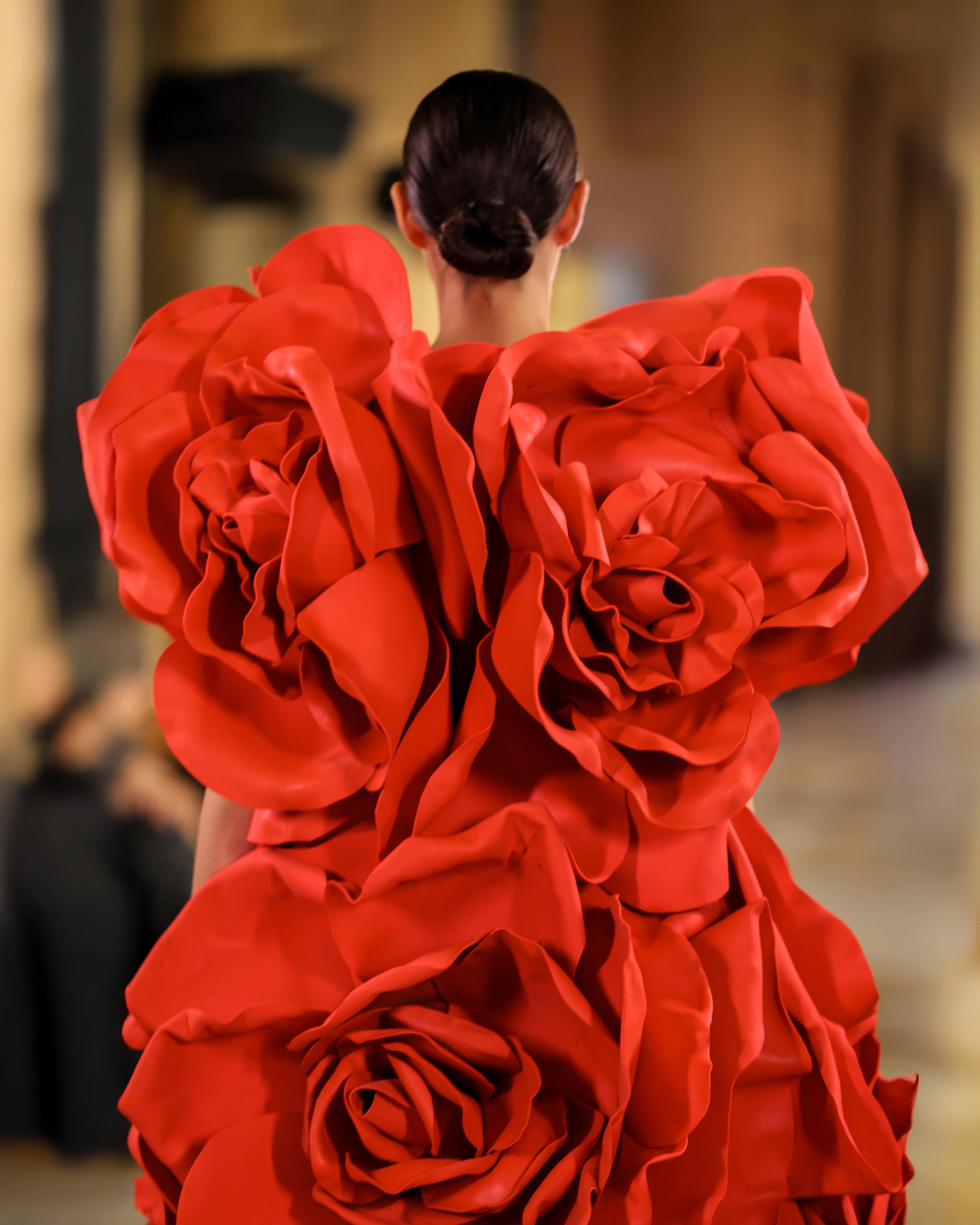 Close back view of model in red gown made of large sculpted rose petals